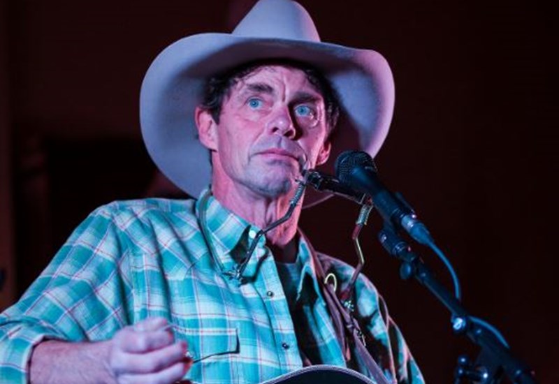 Rich Hall with hat and guitar