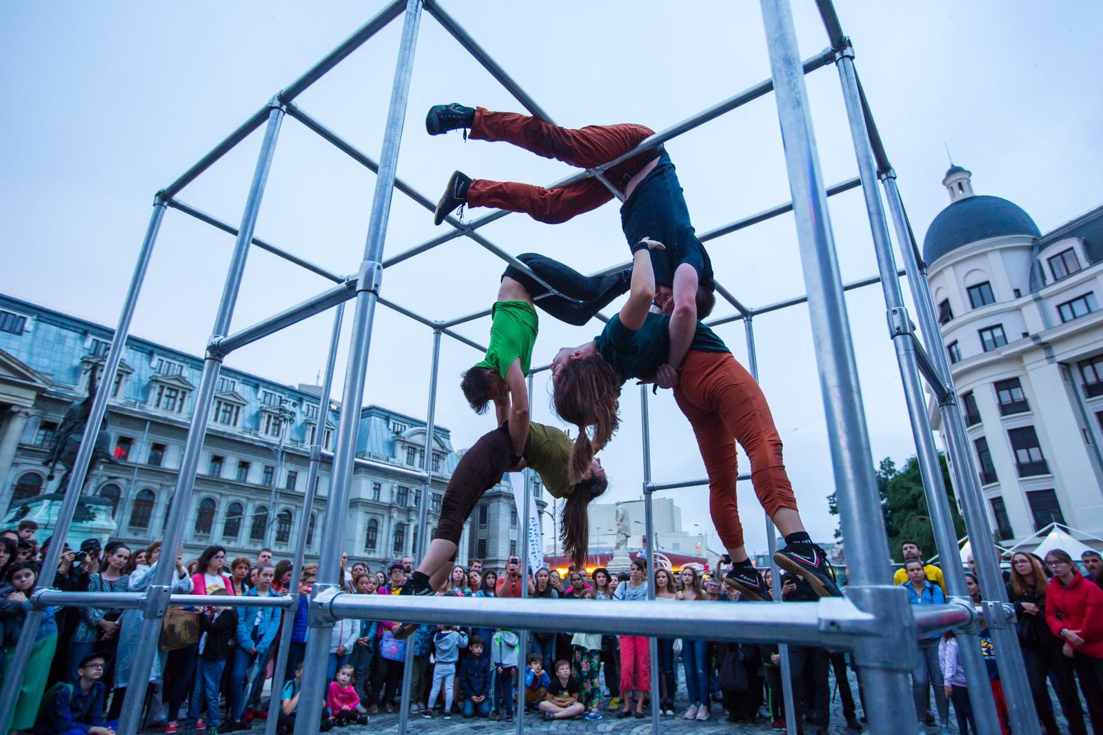 Motionhouse perform inside giant cage surrounded by standing audience and buildings